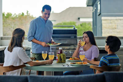 Family enjoying dinner from their propane grill outside